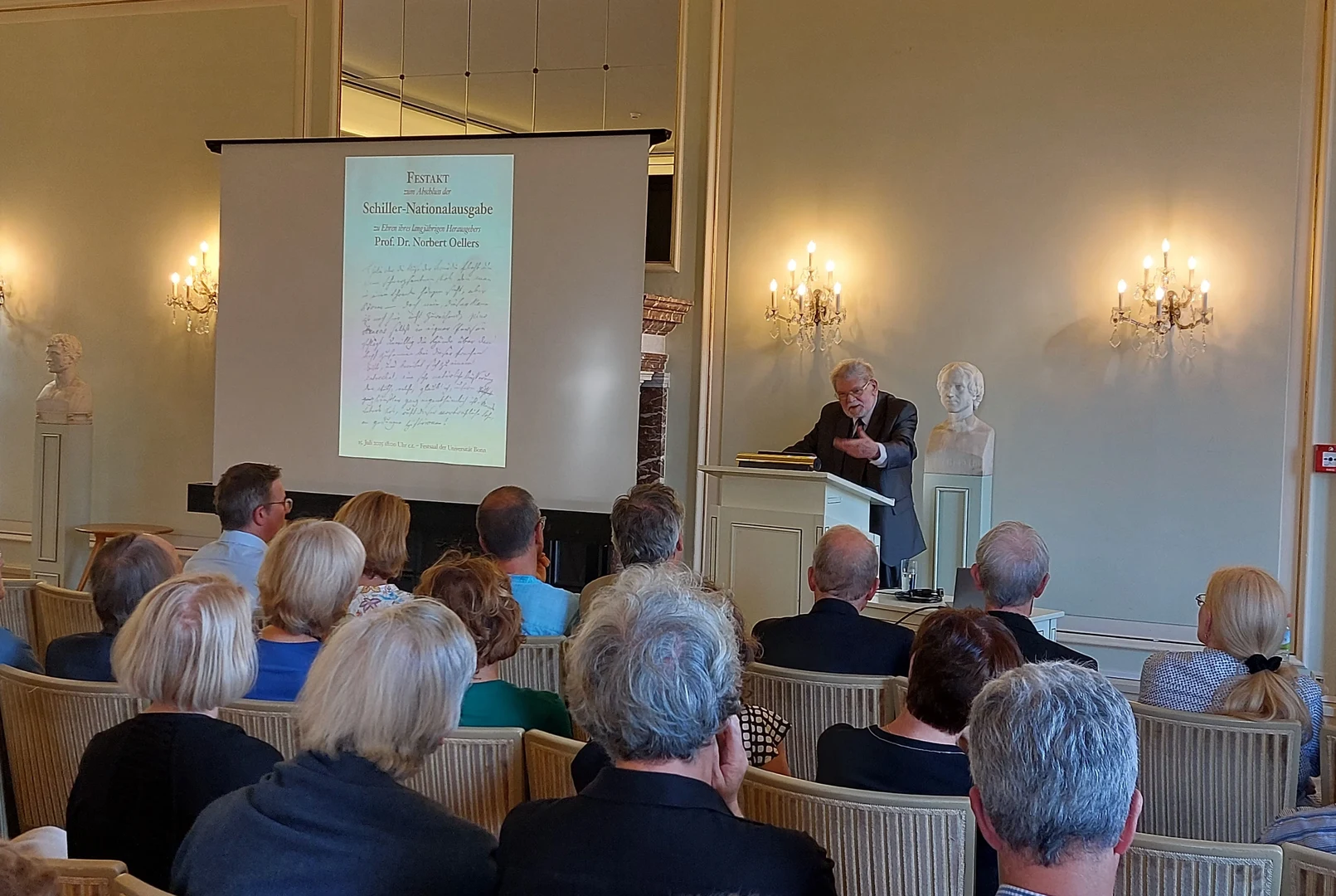 Eine Wissenschaftlerin und ein Wissenschaftler arbeiten hinter einer Glasfassade und mischen Chemikalien mit Großgeräten.