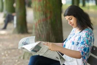 Eine Frau liest Zeitung am Hofgarten