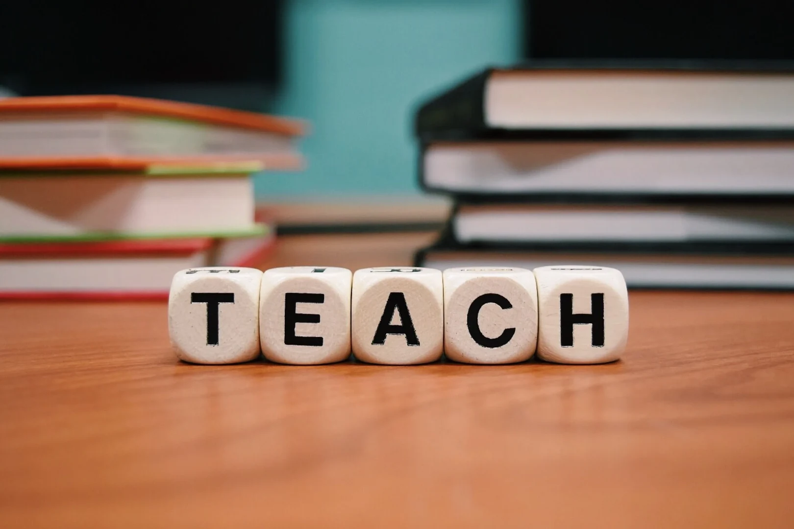 Fünf Würfel mit Buchstaben, die das Wort TEACH bilden